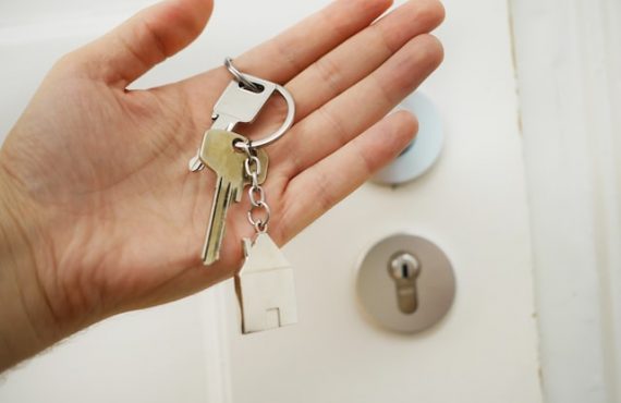 white hand holding keys next to white door